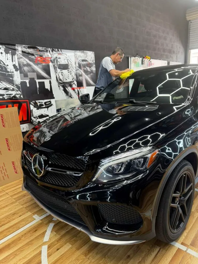 Black Mercedes SUV with dark carbon window tint inside a professional automotive shop