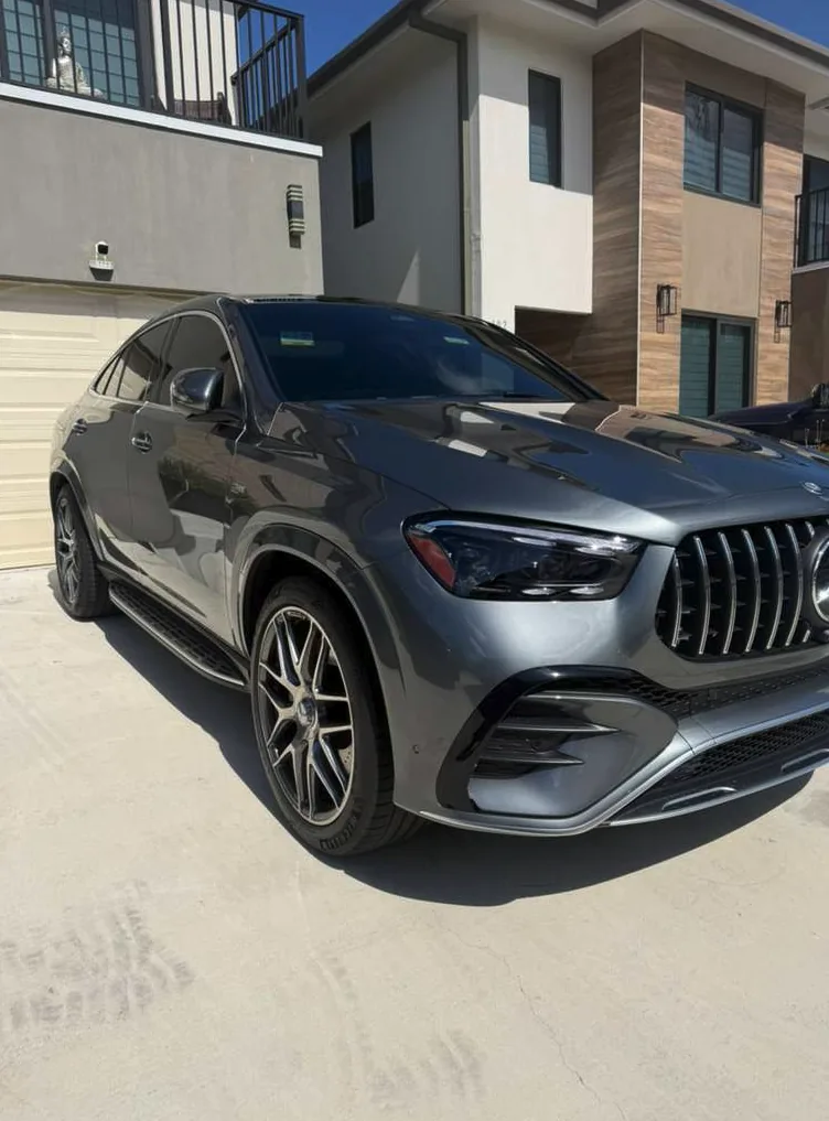 Gray Mercedes SUV with carbon window tint parked outside a modern residence