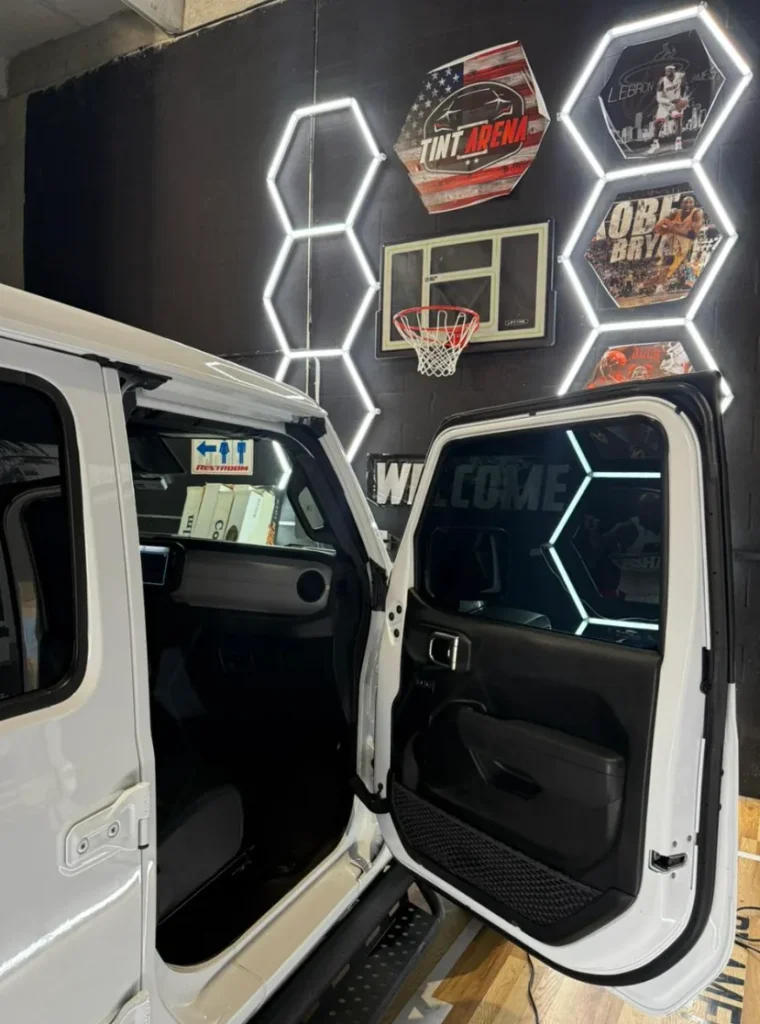 Open rear door of a white Jeep showing newly installed carbon window tint