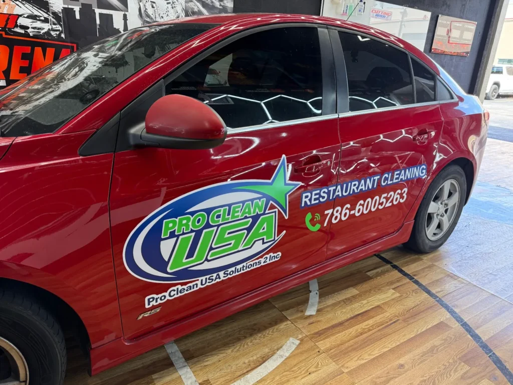 Red commercial sedan with business graphics and dark carbon window tint
